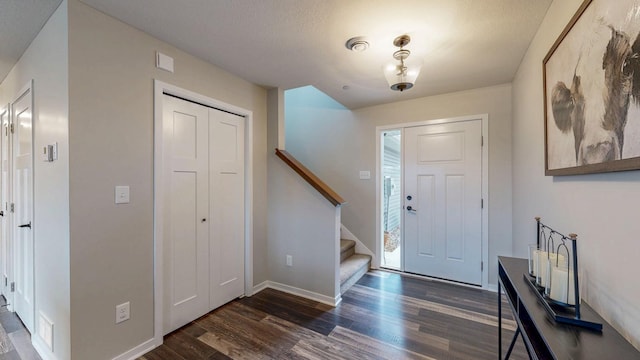 entrance foyer featuring dark wood-type flooring, stairway, and baseboards