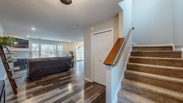 stairs with a stone fireplace, recessed lighting, baseboards, and wood finished floors