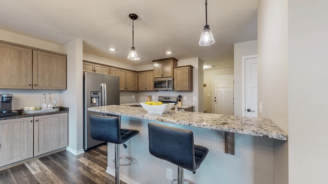 kitchen featuring dark wood-style flooring, stainless steel appliances, a kitchen bar, and light stone countertops