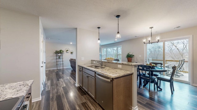 kitchen featuring light stone countertops, dark wood finished floors, a sink, stainless steel appliances, and a textured ceiling