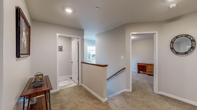 hall with an upstairs landing, recessed lighting, light carpet, and baseboards