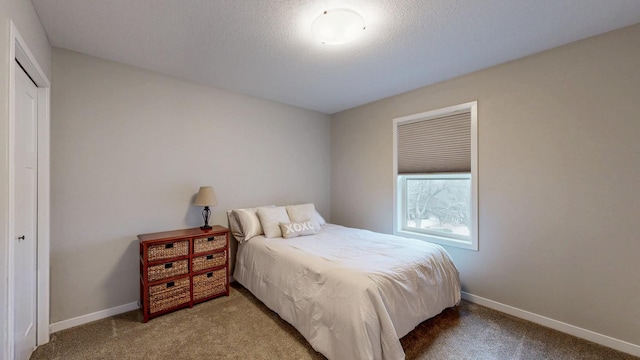 bedroom with carpet, baseboards, a closet, and a textured ceiling