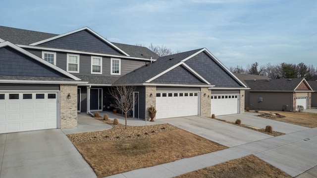 craftsman inspired home with an attached garage, brick siding, roof with shingles, and driveway