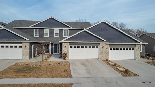 view of front of property featuring concrete driveway, brick siding, a garage, and roof with shingles