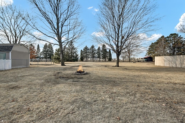 view of yard with a shed, an outdoor fire pit, fence, and an outdoor structure