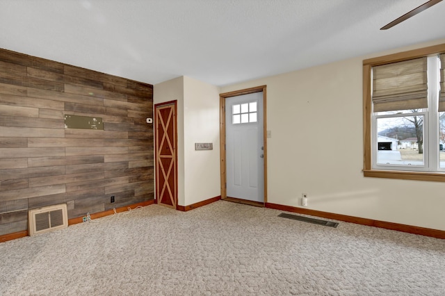 interior space featuring an accent wall, baseboards, wooden walls, and visible vents