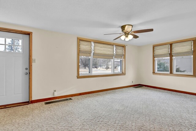 unfurnished room featuring carpet floors, visible vents, plenty of natural light, and baseboards