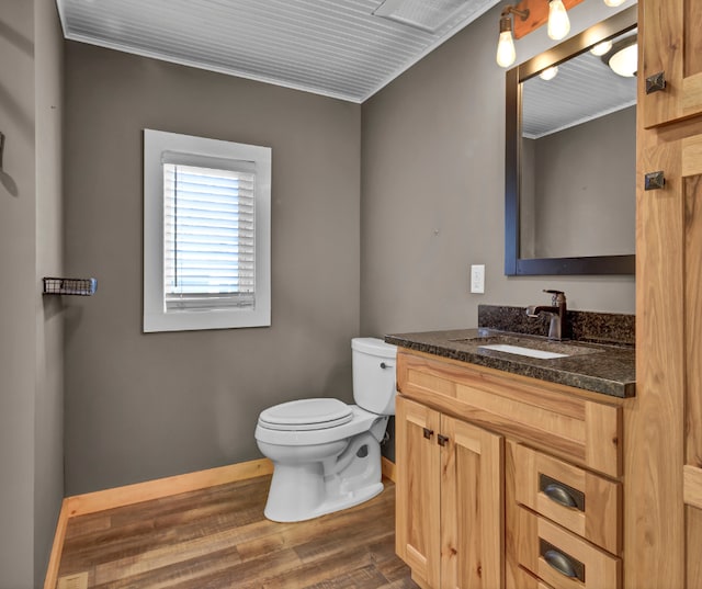 bathroom with vanity, wood finished floors, toilet, and baseboards