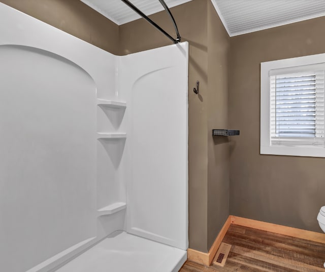 full bath featuring a shower, wood finished floors, toilet, and baseboards