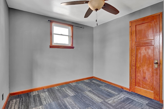 carpeted spare room featuring ceiling fan and baseboards