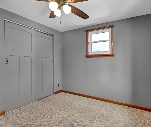 unfurnished bedroom featuring light carpet, a ceiling fan, baseboards, and a closet