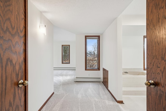 hall featuring carpet floors, baseboards, baseboard heating, and a textured ceiling