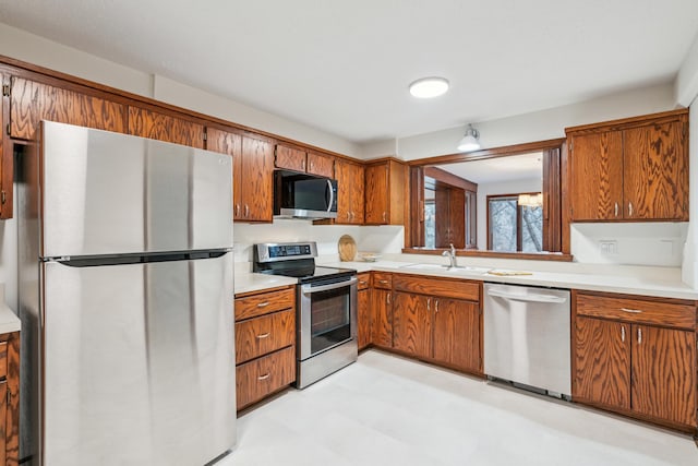 kitchen with stainless steel appliances, a sink, light countertops, and brown cabinets