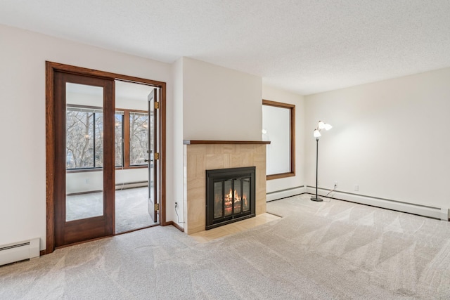 unfurnished living room featuring a baseboard radiator, a tiled fireplace, baseboard heating, light carpet, and a textured ceiling