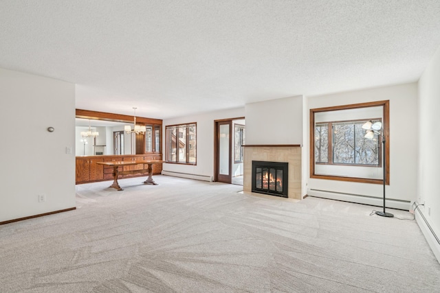 unfurnished living room featuring a chandelier, a baseboard radiator, and a healthy amount of sunlight