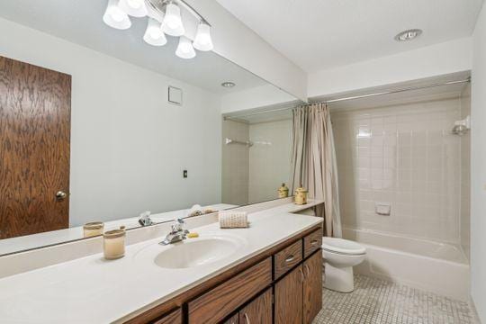 bathroom featuring vanity, shower / bath combination with curtain, tile patterned flooring, and toilet