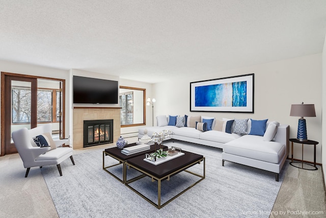 living area featuring light carpet, a textured ceiling, and a tile fireplace