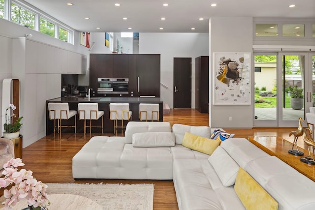 living room featuring recessed lighting, a high ceiling, and wood finished floors