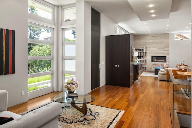 living room featuring a high ceiling, a fireplace, recessed lighting, and light wood-style floors