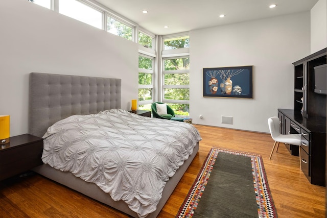 bedroom featuring a wall of windows, recessed lighting, and wood finished floors