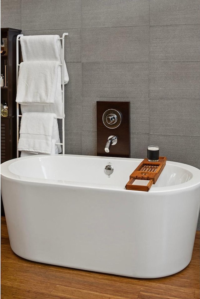 bathroom with a freestanding bath and wood finished floors