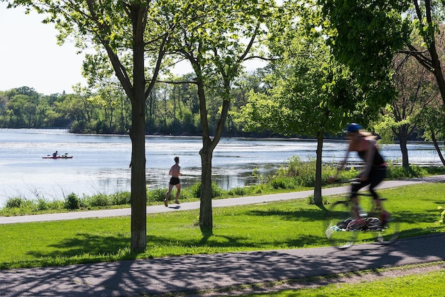 view of community with a lawn, a water view, and a view of trees