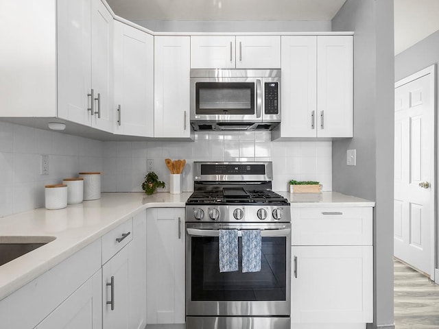 kitchen featuring backsplash, stainless steel appliances, and white cabinetry