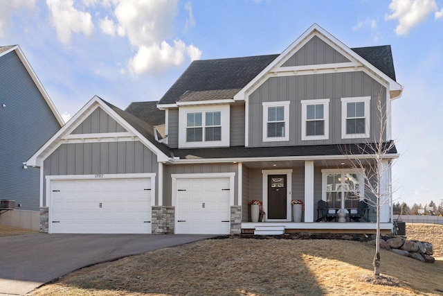 view of front facade featuring aphalt driveway, a shingled roof, covered porch, board and batten siding, and a garage