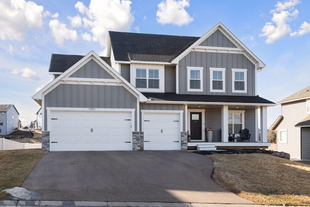 view of front of home with board and batten siding, covered porch, driveway, and a shingled roof