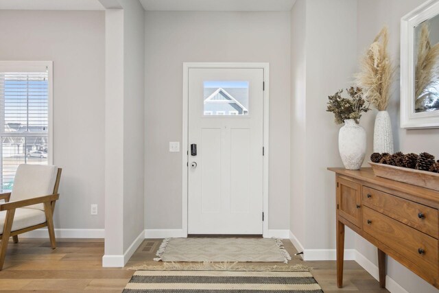 foyer featuring light wood-type flooring, plenty of natural light, and baseboards