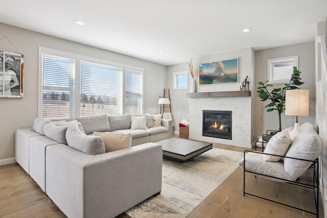 living room featuring a tiled fireplace, baseboards, wood finished floors, and recessed lighting