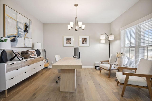 office space featuring light wood-type flooring, an inviting chandelier, and baseboards