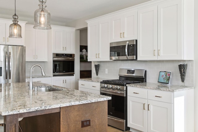 kitchen featuring tasteful backsplash, white cabinets, stainless steel appliances, pendant lighting, and a sink