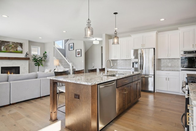 kitchen featuring light wood-style floors, stainless steel appliances, a sink, and open floor plan