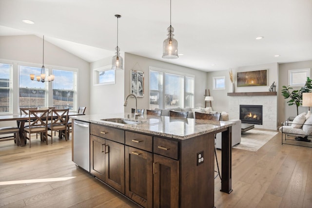 kitchen with dark brown cabinetry, dishwasher, light wood-type flooring, a fireplace, and a sink