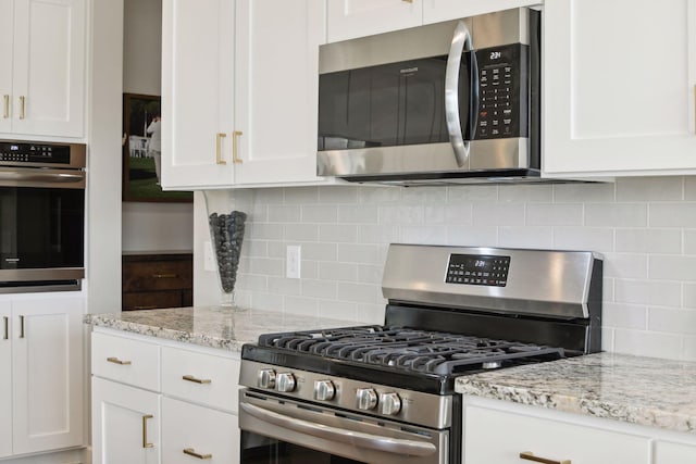 kitchen with appliances with stainless steel finishes, white cabinetry, and backsplash