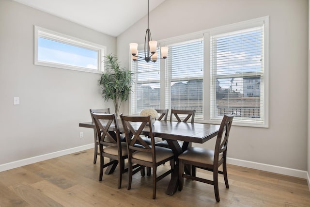 dining area featuring light wood finished floors, baseboards, vaulted ceiling, and a notable chandelier