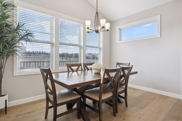 dining room with lofted ceiling, light wood-style flooring, baseboards, and a chandelier