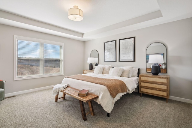 carpeted bedroom with baseboards and a tray ceiling