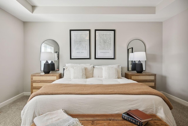 bedroom with a tray ceiling, baseboards, and carpet flooring