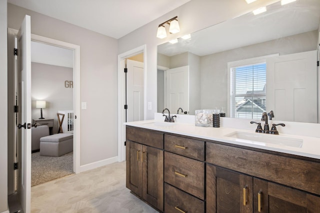 bathroom with double vanity, a sink, and baseboards