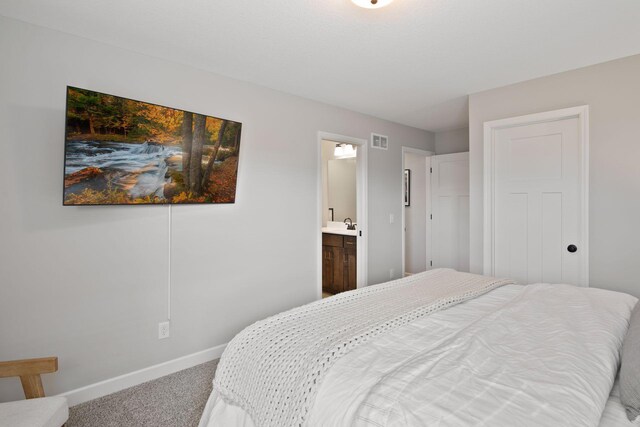 carpeted bedroom featuring baseboards, visible vents, and connected bathroom