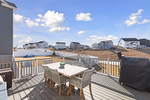 wooden deck with a residential view, outdoor dining area, and a grill