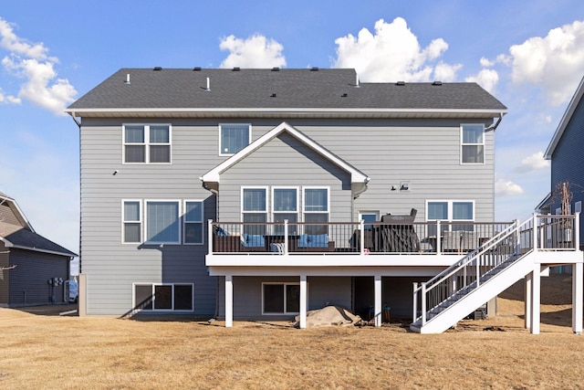 rear view of property featuring a shingled roof, a yard, a wooden deck, and stairs