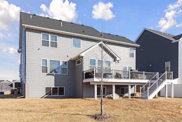 rear view of property featuring a shingled roof, a yard, stairway, and a wooden deck