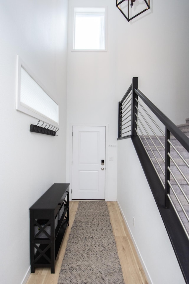 doorway featuring baseboards, stairway, and wood finished floors