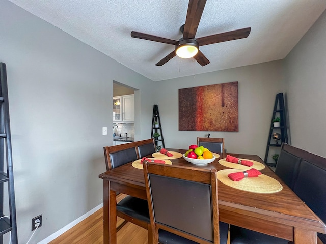 dining space with light wood-type flooring, ceiling fan, a textured ceiling, and baseboards