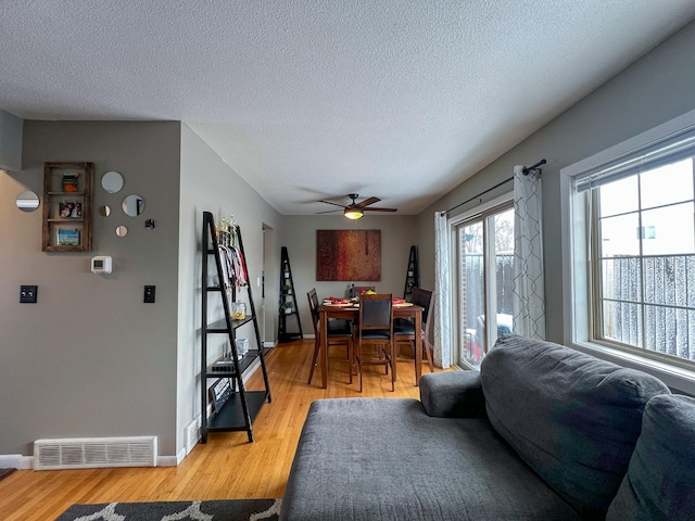 interior space with baseboards, visible vents, a textured ceiling, and light wood finished floors