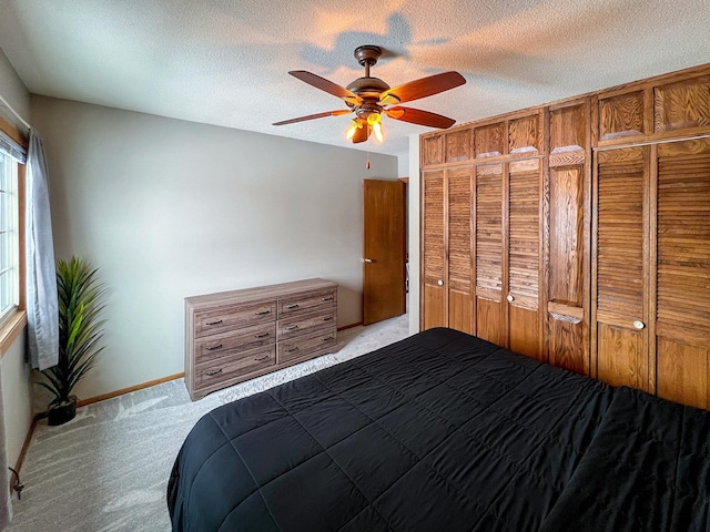 unfurnished bedroom with a textured ceiling, ceiling fan, carpet, and baseboards