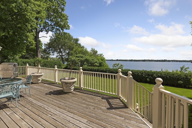 wooden terrace with grilling area, a water view, and a lawn